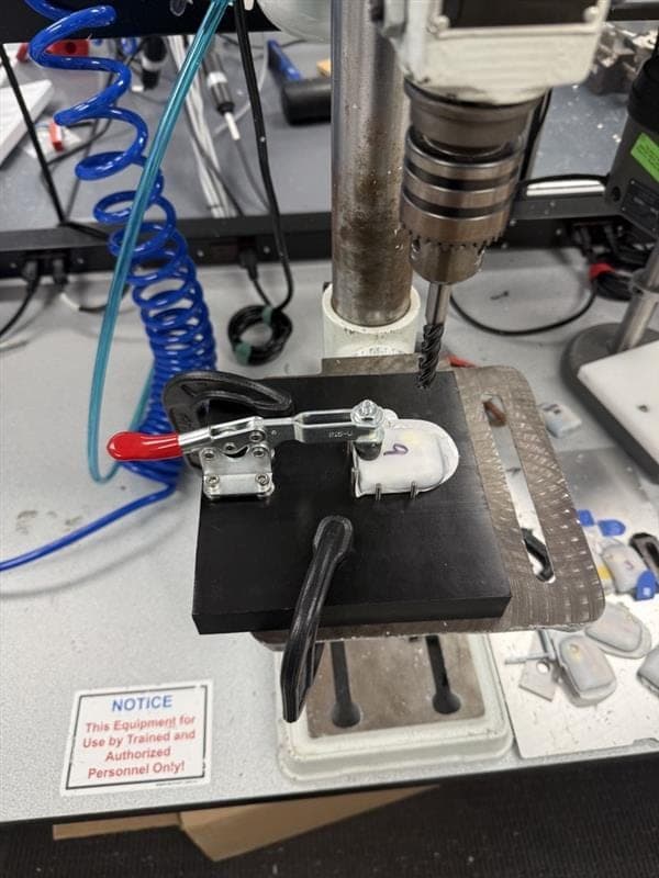 Teardown fixture on the drill-press table with a device clamped in position
