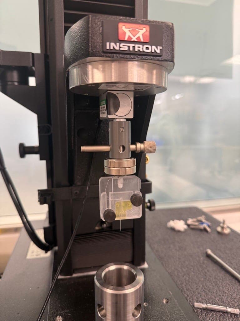 Clamp fixture mounted under the Instron load cell during an insertion-force run